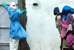 Photo of a health worker in full protective gear beckoning to passer-bys
