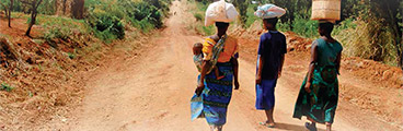 Photo of three with women with supplies on their head.
