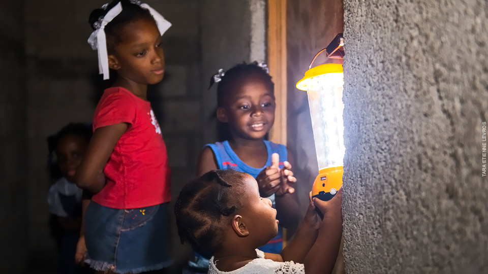 Girls in Haiti admire a solar powered lamp.