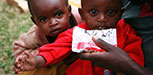 Two children receive supplementary food from a packet