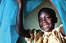 A child smiles beneath mosquito nets