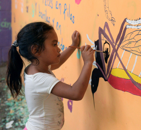 young girls painting a mural of a mosquito on a wall