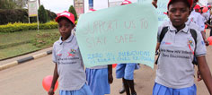 Two girls carry a sign saying Support Us to Stay Safe. Zero HIV Infections is everyone's responsibility.