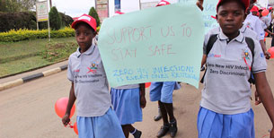 Two girls carry a sign saying Support Us to Stay Safe. Zero HIV Infections is everyone's responsibility.