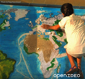 Open IDEO - A woman kneels on a map of the world