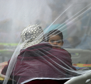 A mother and child beneath a protective mosquito net'