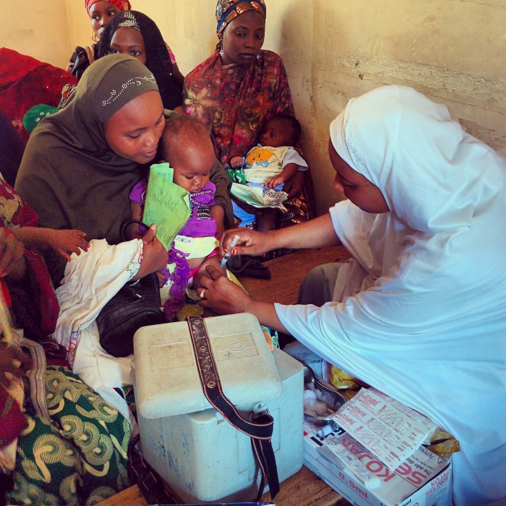A woman administers a vaccine to an infant in Nigeria.