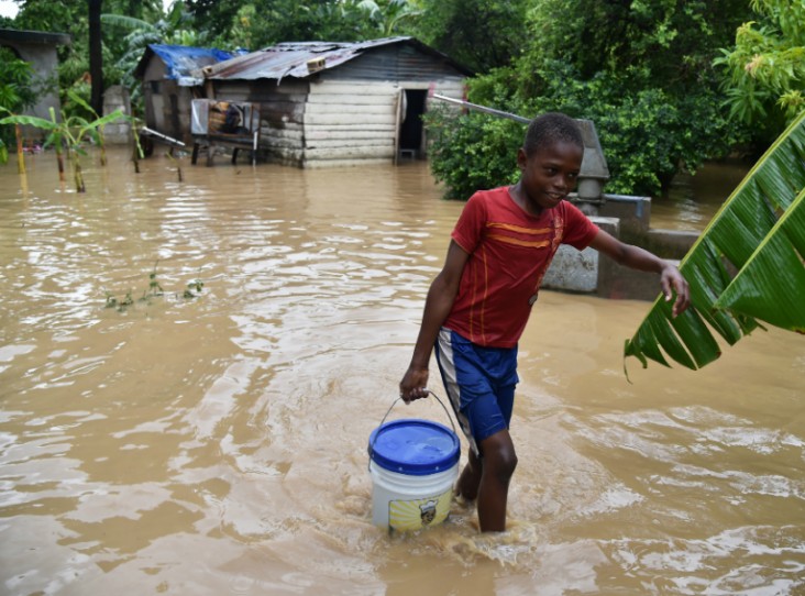 Jonnathan fetches clean water for his mother cleaning his home flooded by the overflowing of the La Rouyonne river