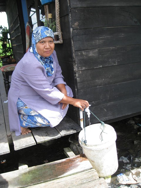 A woman fetching water from her own water tap in Medan, Indonesia.