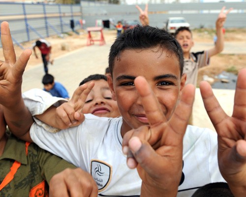 Internally displaced Libyan children flash victory signs while playing in a refugee camp in the eastern rebel stronghold of Beng