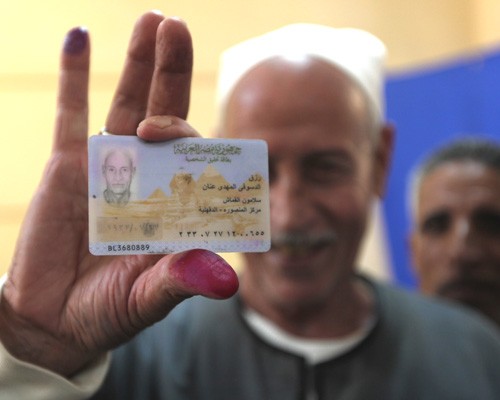 Egyptian Rezq Anan shows his ID card and ink-stained finger after casting his vote at a polling station in Mansura, March 19, 20