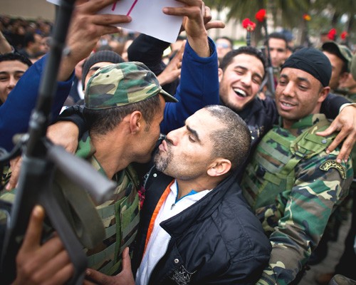 Tunisian protesters kiss soldiers during a demonstration against the presence of the toppled ruling party in the transitional go