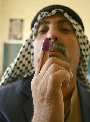 An Iraqi man looks at his finger stained with indelible ink at a polling station in Basra, Jan. 30, 2005.