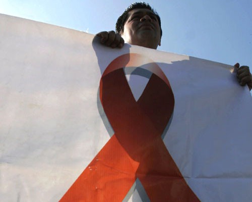 A man holds a banner depicting a red ribbon during a march Dec. 1, 2008, in San Salvador on World AIDS Day. Governments across t
