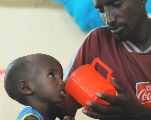 Aden, a 3-year-old Somali refugee recovering from severe malnutrition, is fed by his father at a stabilization center in Hagader