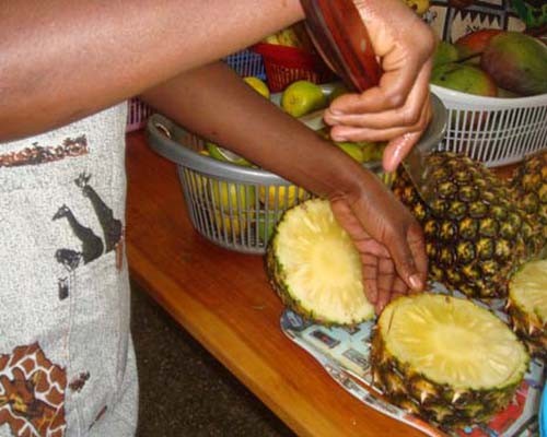 A mother participating in a nutrition education program at Rwanda’s Kibagabaga Hospital cuts pineapple during a fruit salad demo