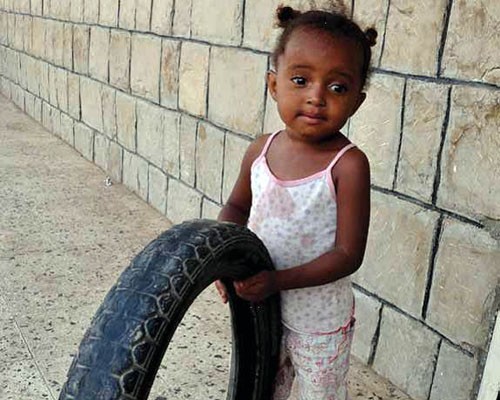 A 3-year-old girl in Lahj plays with a tire.
