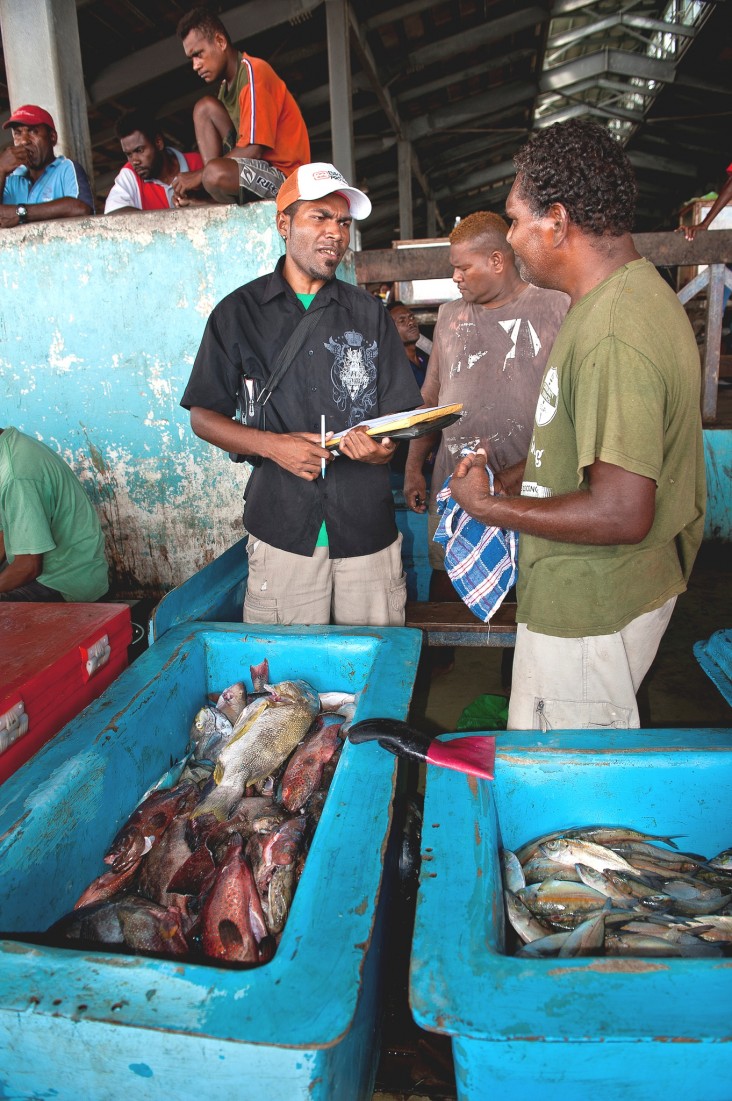 Patrick Ketete, surveyor for the Ministry of Fisheries, interviews a vendor at the Honiara main market.