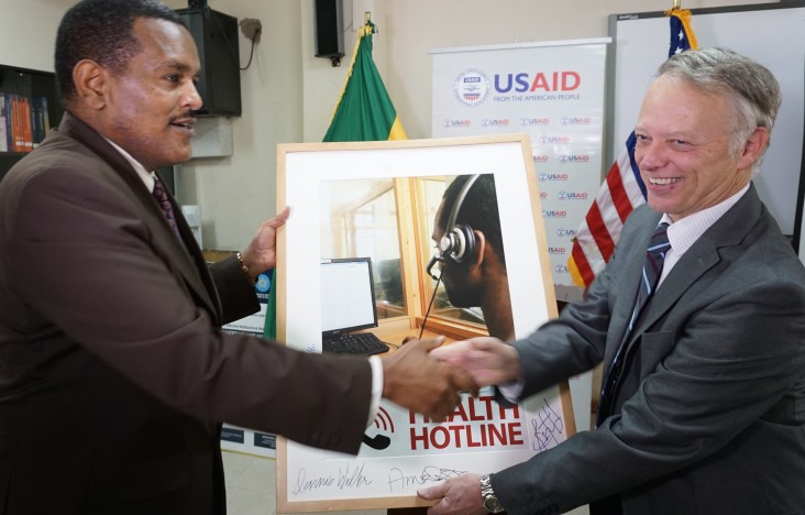 USAID Ethiopia Mission Director Dennis Weller hands a photo of the AIDS health hotline to State Minister of Health Dr. Kebede Wo