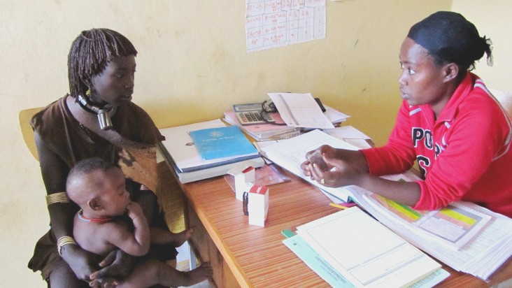 Tarikua Lulayehu, right, the health extension worker at the Aera Keysa health post, assesses and treats 8-month-old Bora Shewki.
