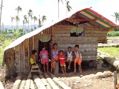 Jeneth Cervantes and her five children in their newly built, USAID-funded emergency shelter.