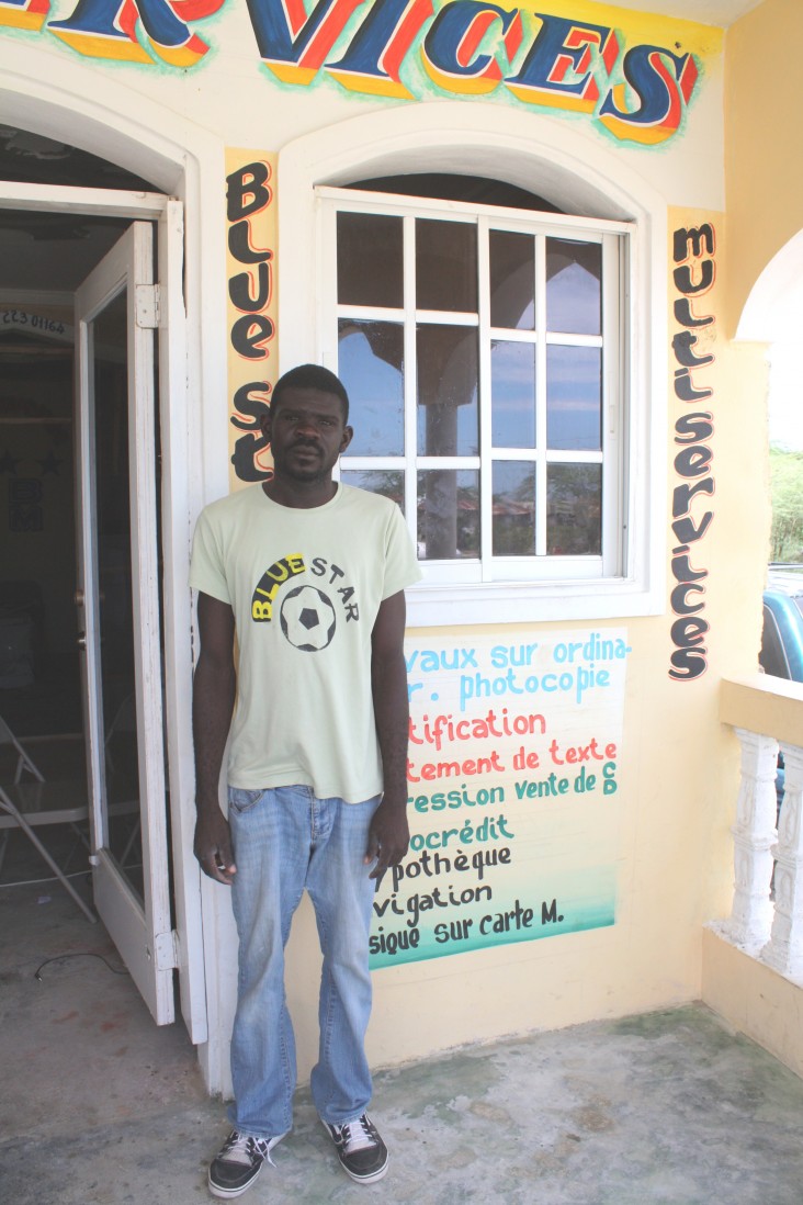 Cadet Luxon, the manager of Cyber Café, stands in front of his shop in Caracol, Haiti, in August 2013.