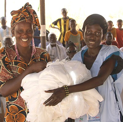 Two Senegalese women receive insecticide-treated bednets through a USAID program.
