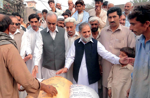 Pakistan Minister of Agriculture Arbab Ayub Jan, center, distributes wheat seed to flood-affected farmers in Khyber Pakhtunkhwa.