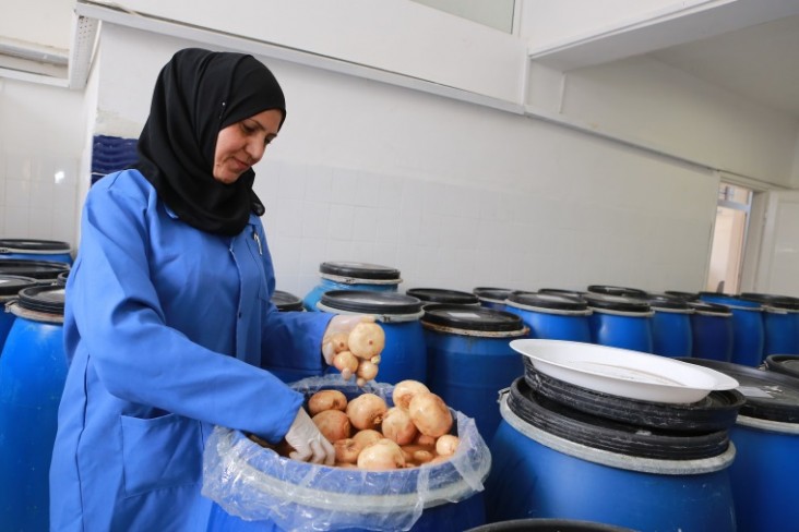 A woman working at a local food processing micro business supported by USAID LENS sorts vegetables to make pickles. 