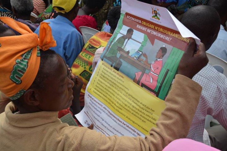 AA woman reads the local language version of the Patient's Charter at a medical camp in Bushenyi, Uganda supported by the USAID-