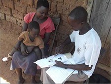 ECD Peer Educator Tonny Anyang of Apua Parish teaches a mother about baby cues. 