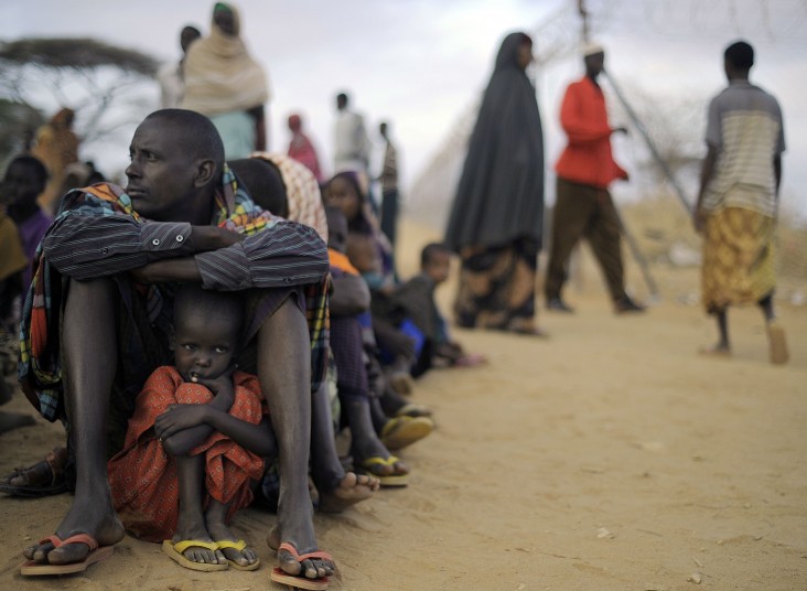 Somali refugee father and daughter sit in line at Dadaab refugee camp in Kenya 