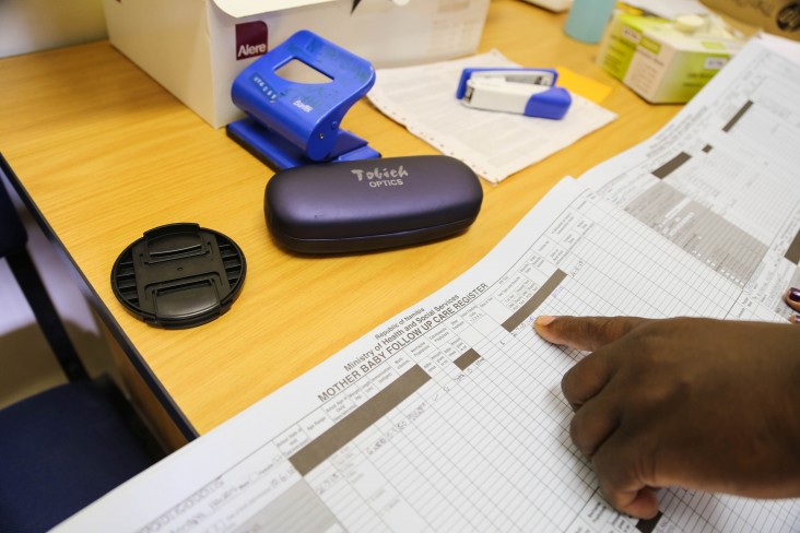 Rightwell Zulu and his team use registers at Nyangana District Hospital to track HIV status for mothers and babies, and to track follow-up visit dates.
