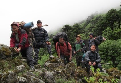 Six Nepali men traverse a mountain ridge during a community-based anti-poaching patrol