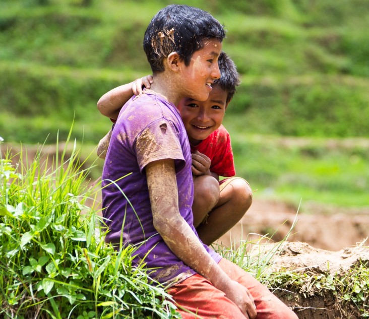 Children watch in admiration as Bigyan Upreti maneuvers the tiller in the field.