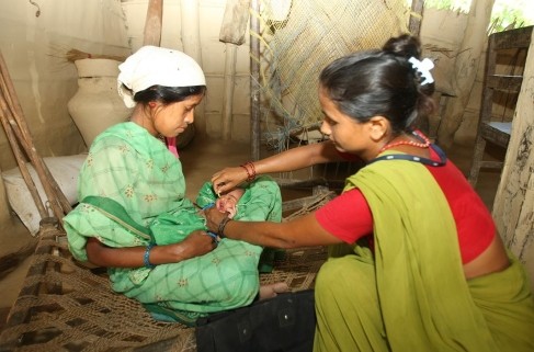 Image of female community health volunteer conducts a postnatal check-up of a young mother and her newborn baby in Nepal.