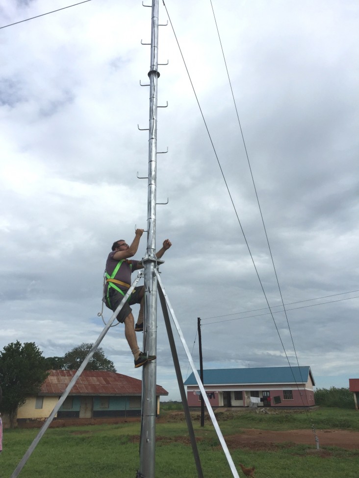 Chris Csikszentmihályi, director of RootIO Community Radio, climbs to set the transmitter at the first station.