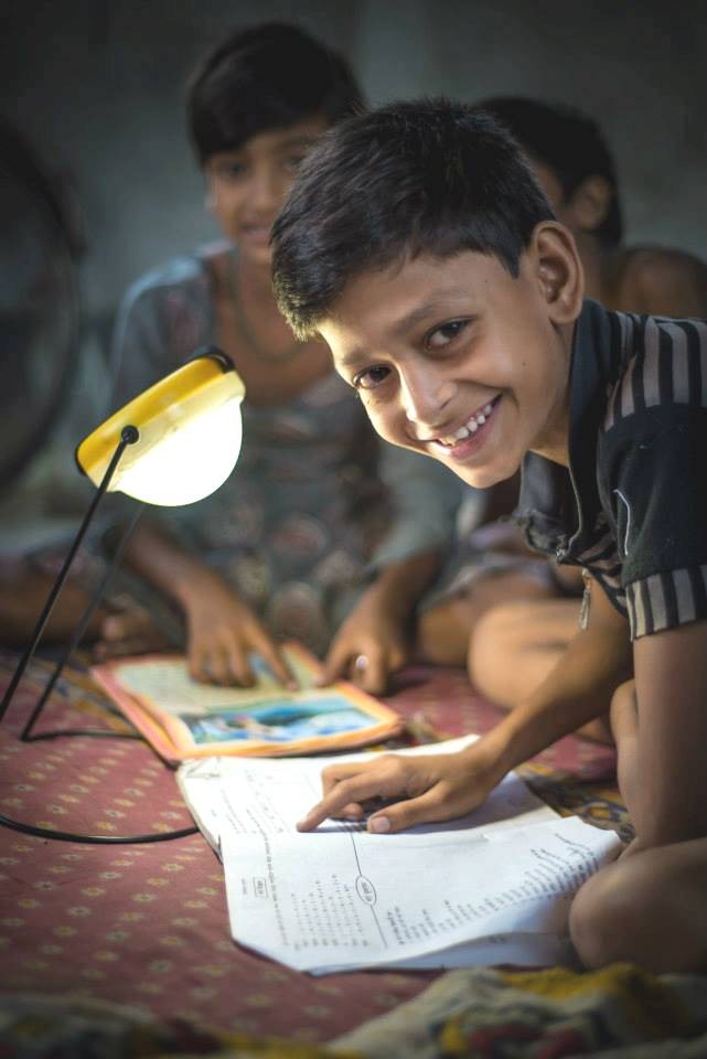 Sundar Mondal, the child of a DCBS client, uses the family’s solar lamp to do his homework.
