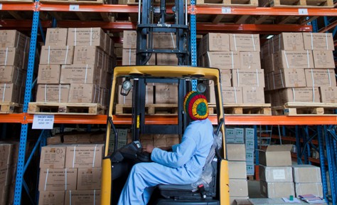 A worker stacks pharmaceuticals in a warehouse.