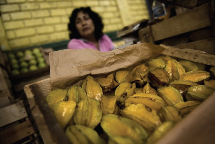 A woman sells star fruit at the wholesale fruit market in Lima, Peru. Extreme poverty in Peru fell to 6 percent in 2012 as coast