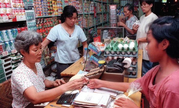 A shop owner receives payment from a girl buying rice in the Philippines.