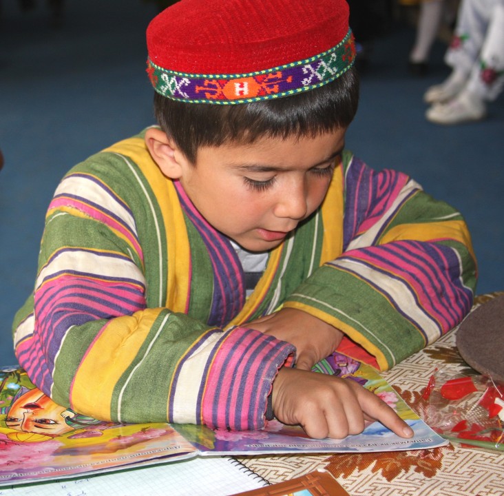 A boy reads from a USAID story book.
