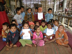 Nepalese children holding school exercise books produced by USAID