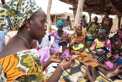 At a monthly community meal, a USAID volunteer shows women how to test salt to ensure it is iodized.