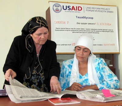 Rural Women Legal Aid Center Director Mukarrama Egamnazarova, left, discusses an article in the USAID Land Reform Project's news