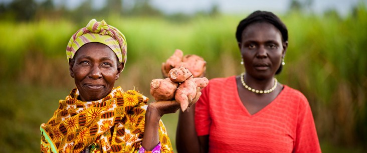 Photo of two women holding up sweet potatoes