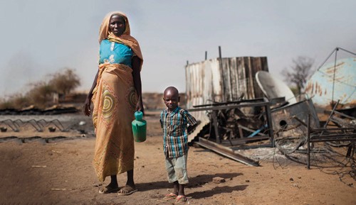 A displaced mother and her child inspect the remains of their burnt house in South Darfur. The United Nation’s High-level Panel 