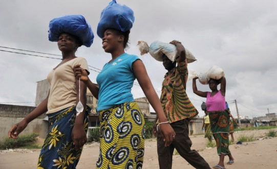 Women carry goods on their heads as they return from shopping in Abidjan. In Côte d’Ivoire, unmet family planning needs, combine