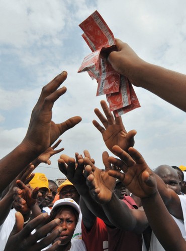 A young woman hands over condoms in a working district of Abidjan, Cote d’Ivoire, as part of an AIDS prevention program. Contrac