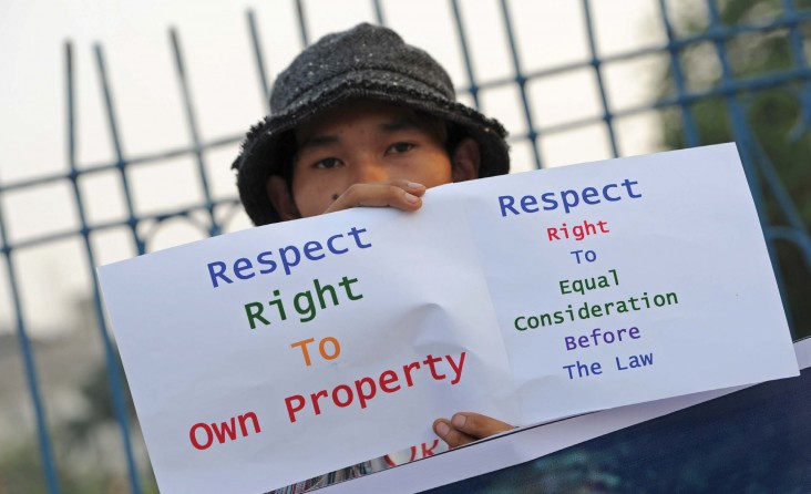A protester holds a placard to mark the anniversary of a crackdown on villagers demonstrating against a Chinese-backed copper mi